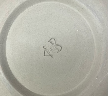 Handmade ceramic bowl with a stamped maker's mark on the underside.