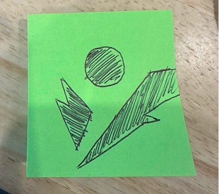 A quick pen sketch of a sun and mountains on a sticky note.